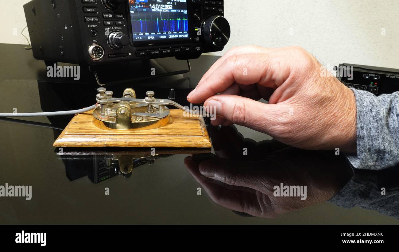 Hand tapping morse code on a telegraph straight key. Stock Photo