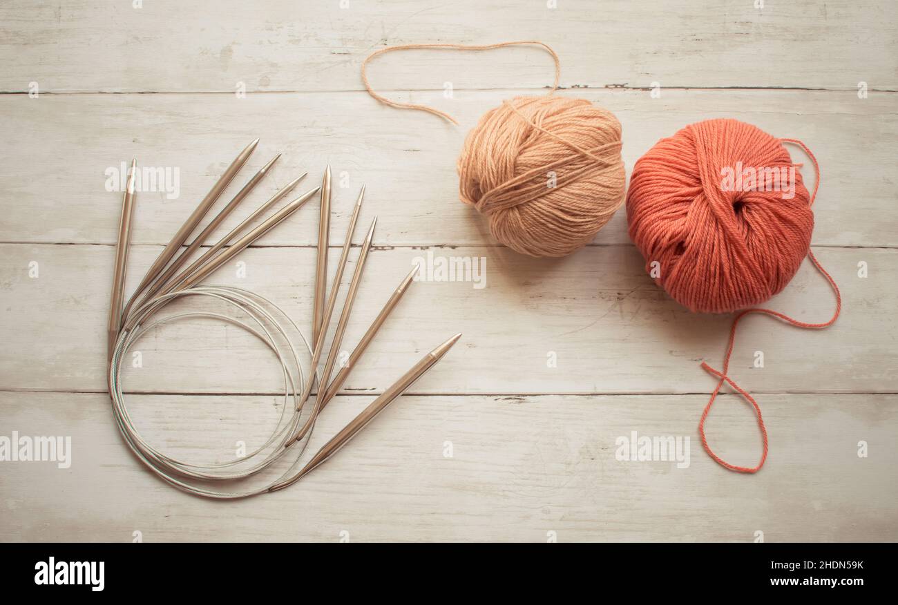 Circular knitting needles and wool yarn on a wooden light surface, hobby and craft Stock Photo