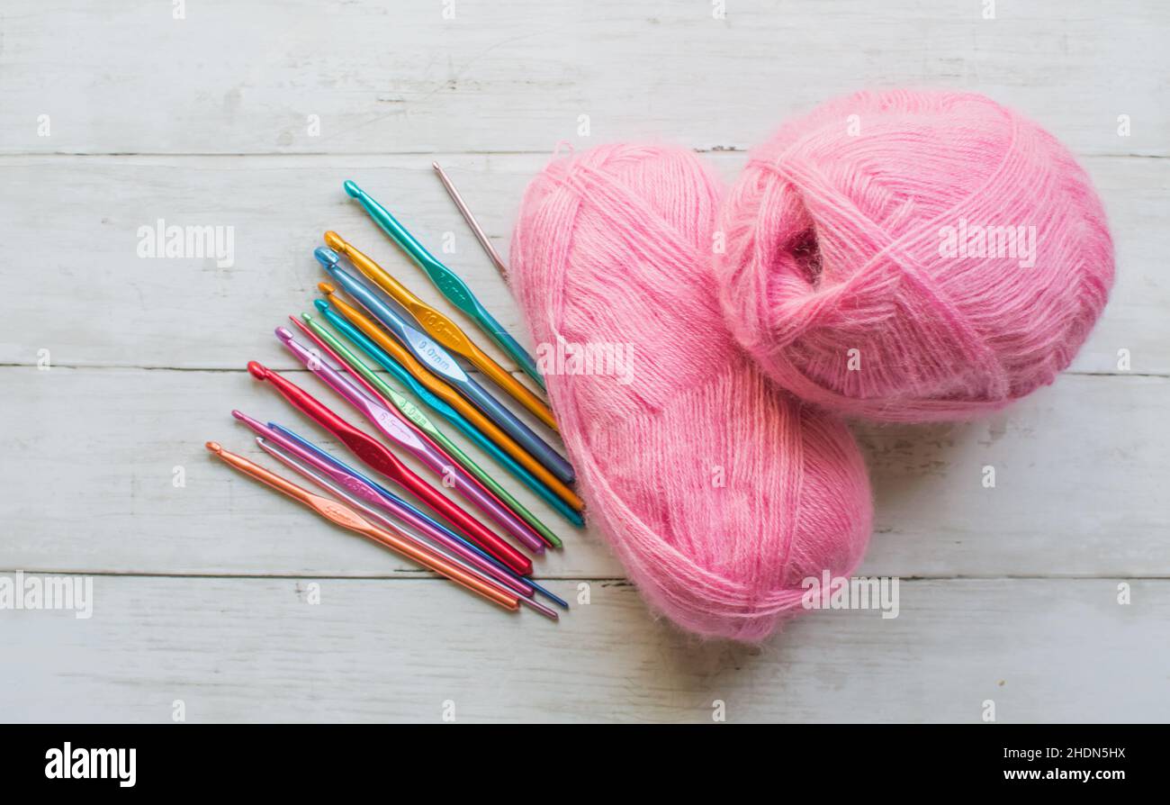 Crochet hooks and pink yarn on a wooden background Stock Photo