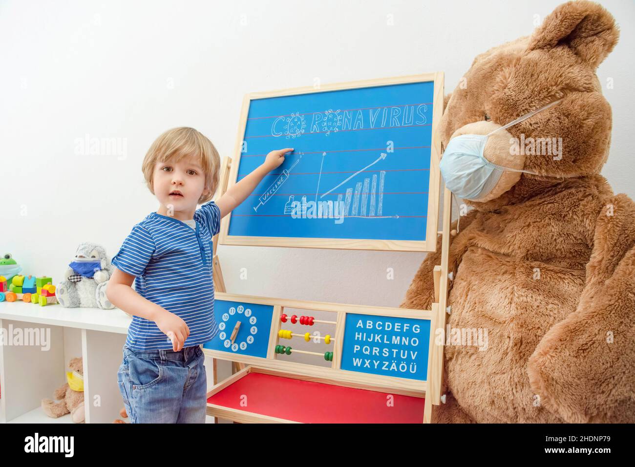Cute child boy in home quarantine and the growing graph of COVID-2019 cases drawn on a chalkboard, during coronavirus pandemic lock down Stock Photo