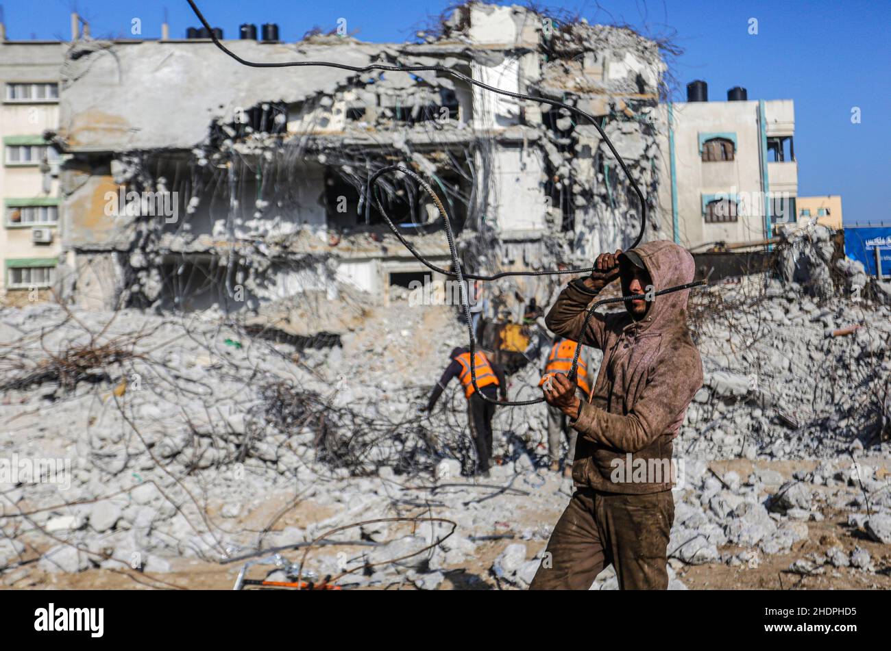 A Palestinian worker collects scrap metal as a bulldozer removes debris ...