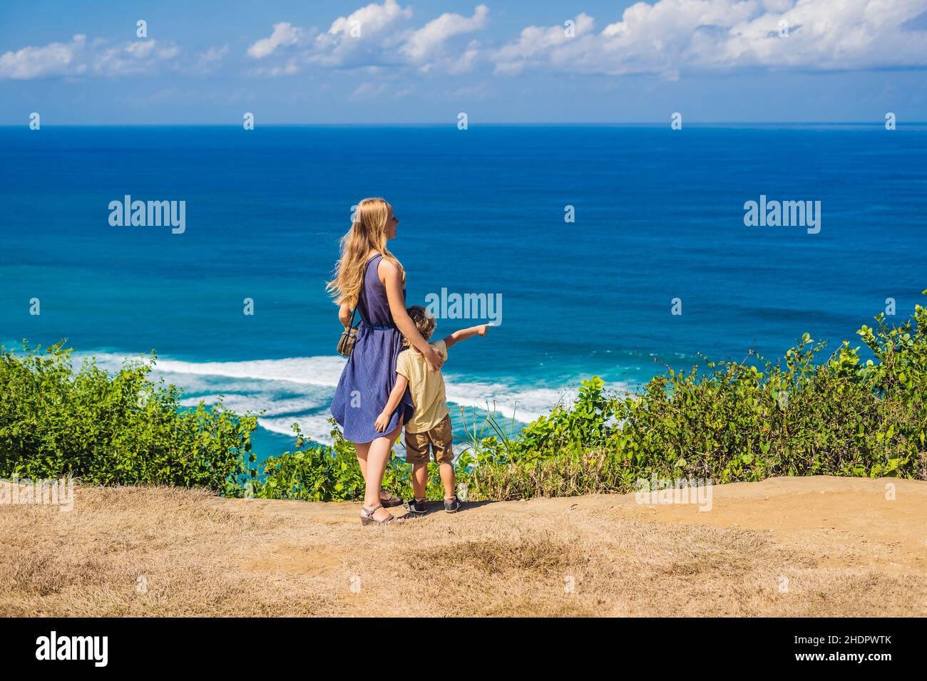 Mom and son travelers on a cliff above the beach. Empty paradise beach