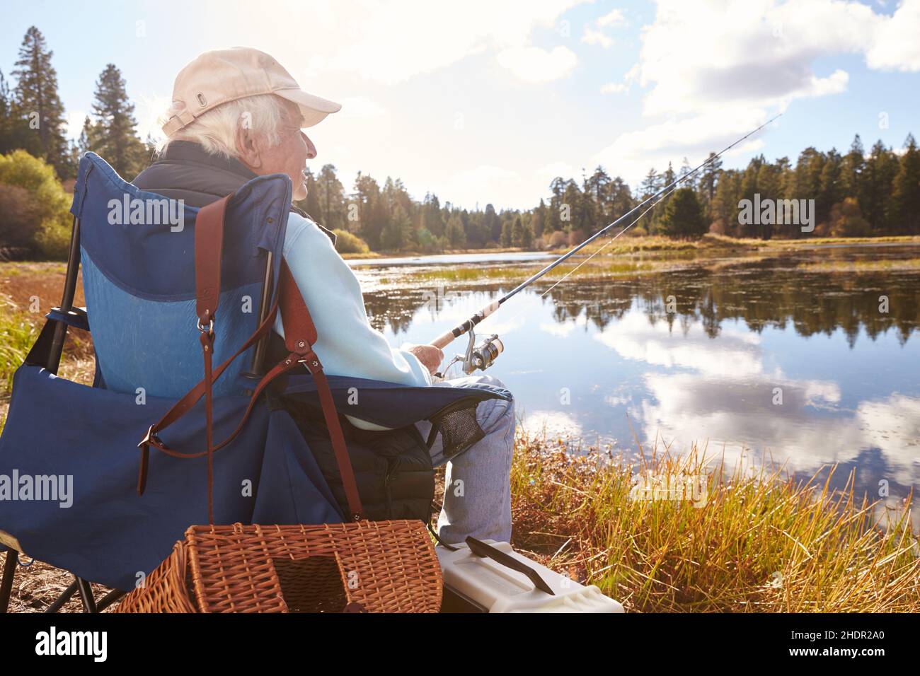 Old man fishing. Senior gray haired fisherman throws a spinning from  shoreside at sunset, twisting a coil. Positive elderly male angling at  lake, rota Stock Photo - Alamy