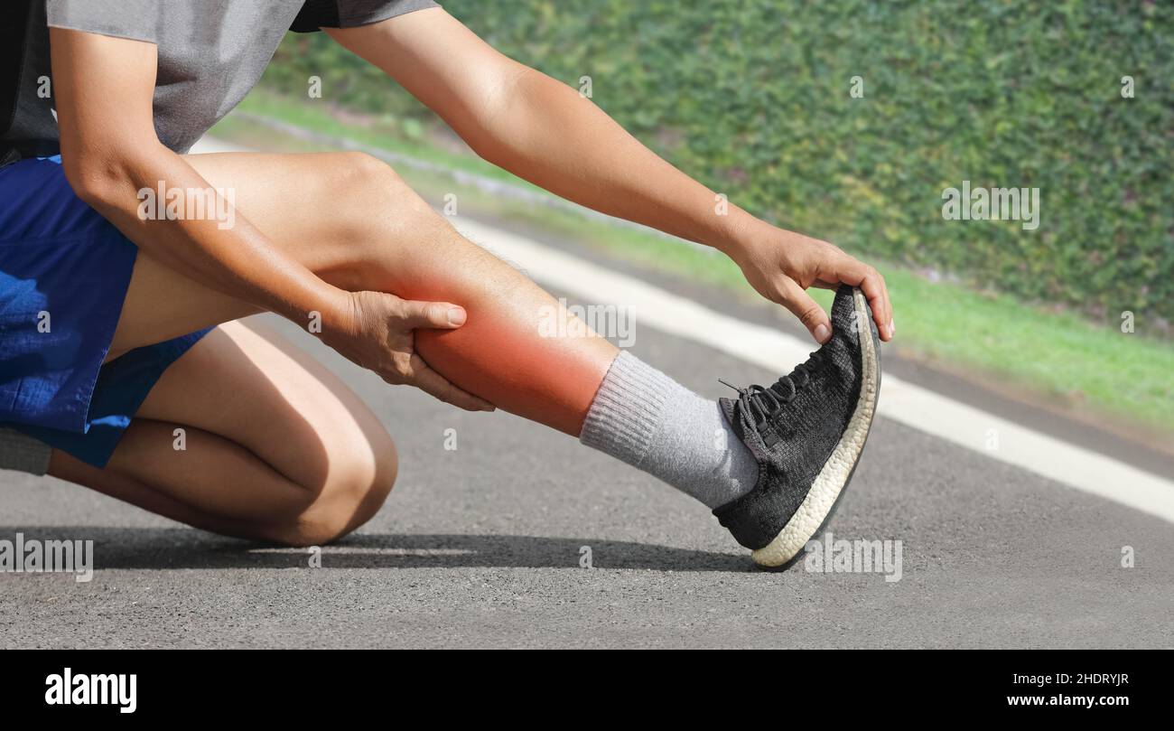 Male middle aged having a cramp while jogging. Stop and massage calf