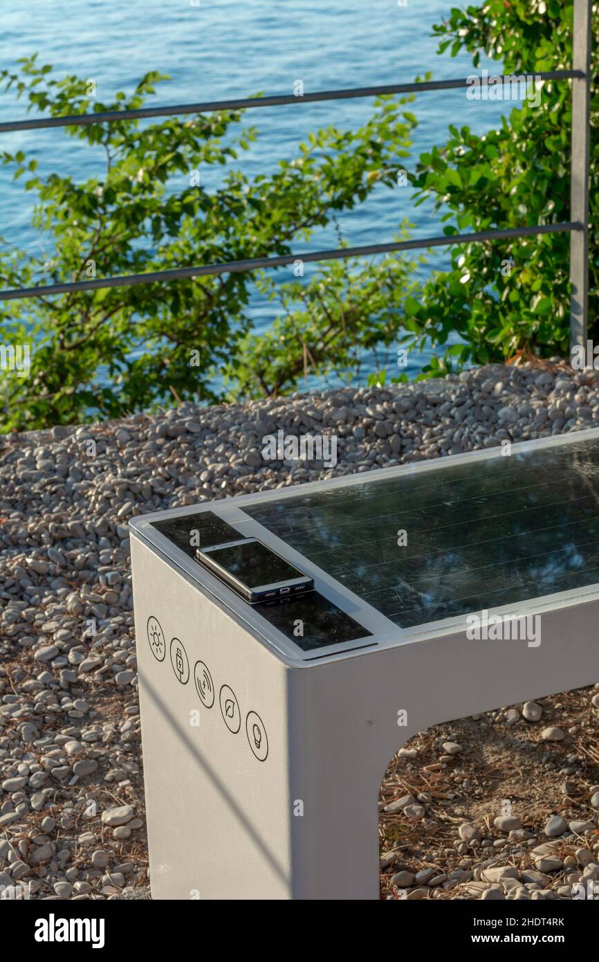 Smart Solar Bench in public place,  powered by sunlight provides wireless and wired charging for users, free wifi and temperature and weather sensors. Stock Photo