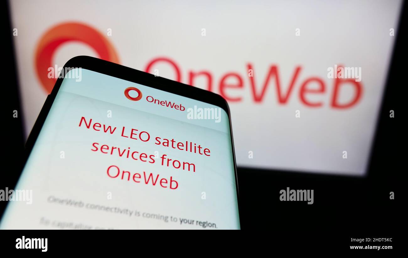 Smartphone with website of satellite company Network Access Associates (OneWeb) on screen in front of logo. Focus on top-left of phone display. Stock Photo