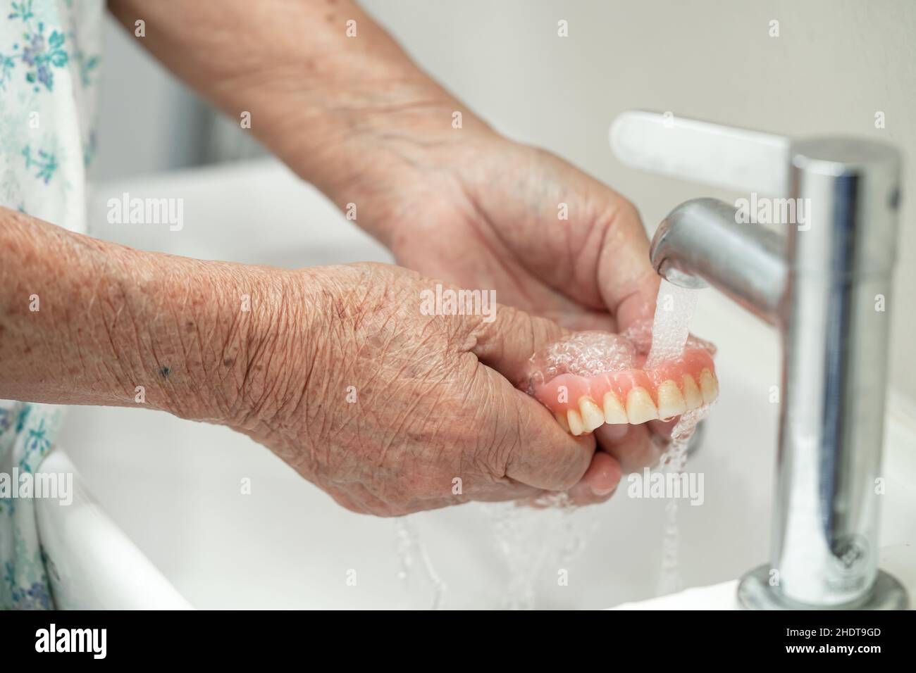 Asian senior or elderly old woman patient holding and washing denture