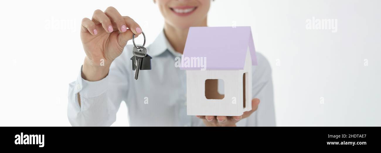 Smiling female agent holding small house and keys Stock Photo - Alamy