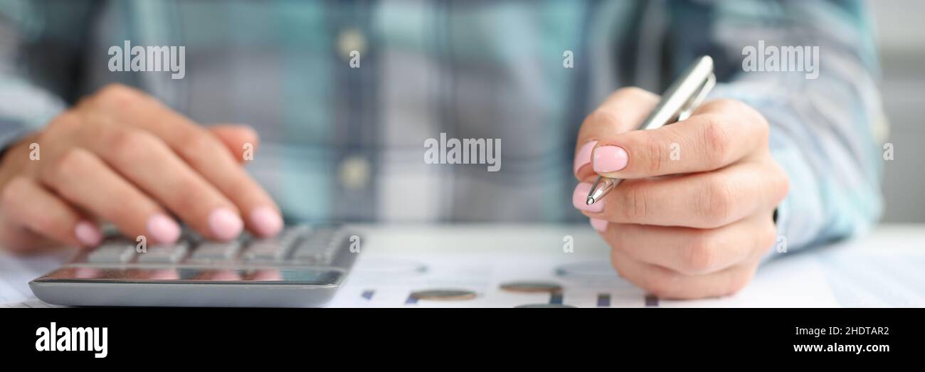 Woman hand holds pen and considers business expenses Stock Photo