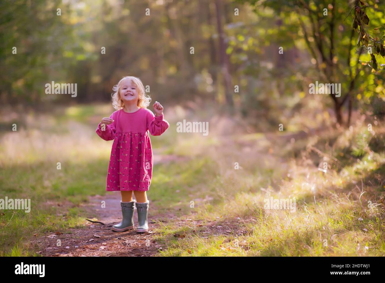 Cute little girl in a pink dress posing outdoors Stock Photo - Alamy