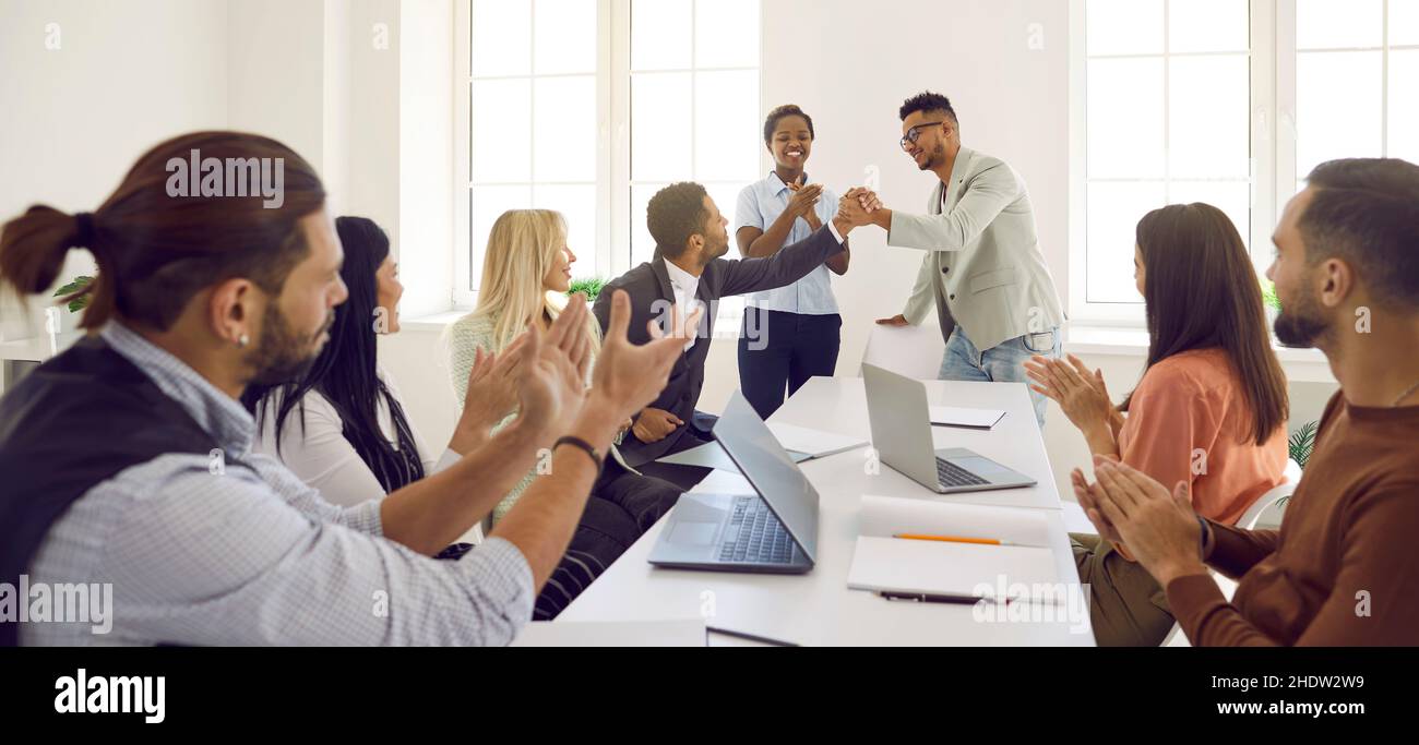 Diverse employees congratulate man on business achievements, excellent work results or promotion. Stock Photo