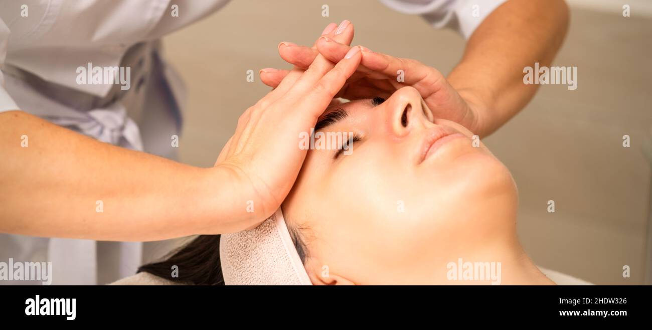 Beautiful young caucasian woman receiving a head massage in a beauty clinic, close up Stock Photo