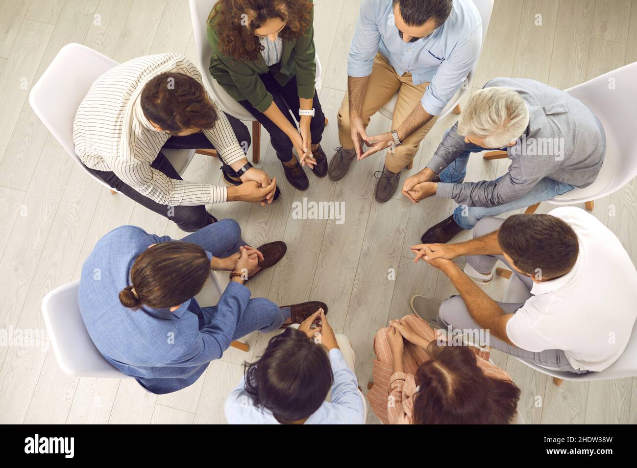 Overhead view of group of people sitting in circle during therapy session with psychiatrist Stock Photo
