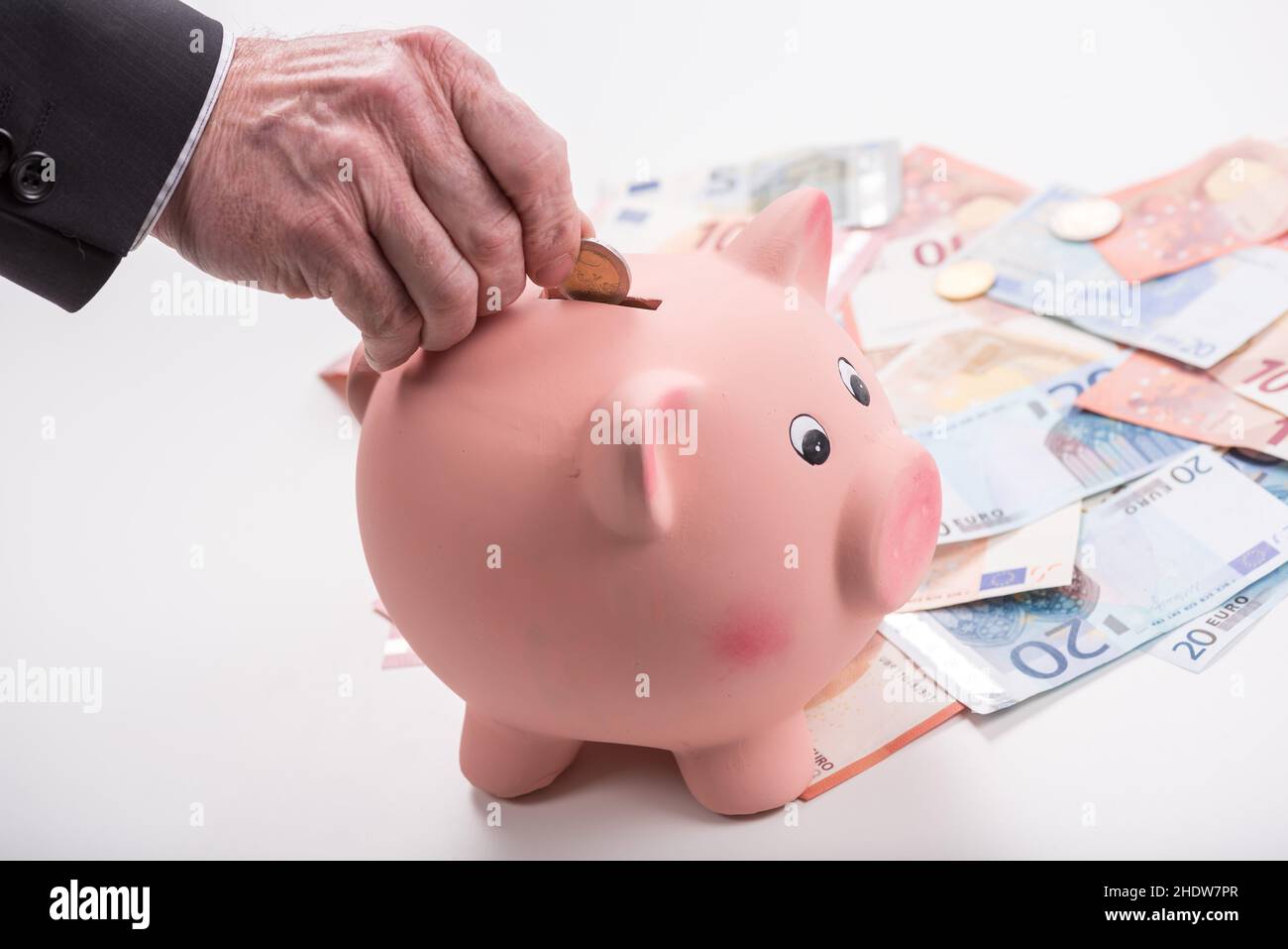 Hand putting a coin into a piggy bank Stock Photo - Alamy