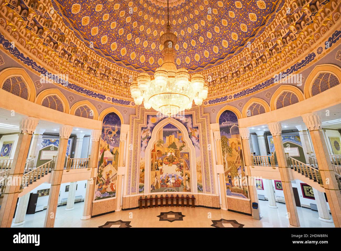 The golden, richly detailed interior atrium with large mural and chandelier. At the Amir Timur museum in Tashkent, Uzbekistan. Stock Photo