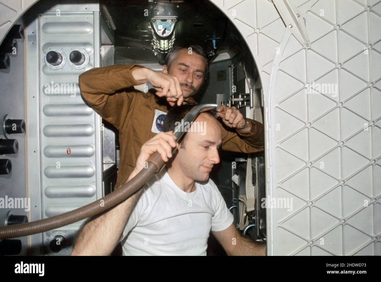 (19 Aug. 1973) --- Scientist-astronaut Owen K. Garriott, Skylab 3 science pilot, trims the hair of astronaut Alan L. Bean, commander, in this onboard photograph from the Skylab Orbital Workshop (OWS) in Earth orbit. Astronaut Jack R. Lousma, pilot, took this picture with a 35mm Nikon camera. Bean holds a vacuum hose to gather in loose hair. The crew of the second manned Skylab flight went on to successfully complete 59 days aboard the Skylab space station cluster in Earth orbit Stock Photo