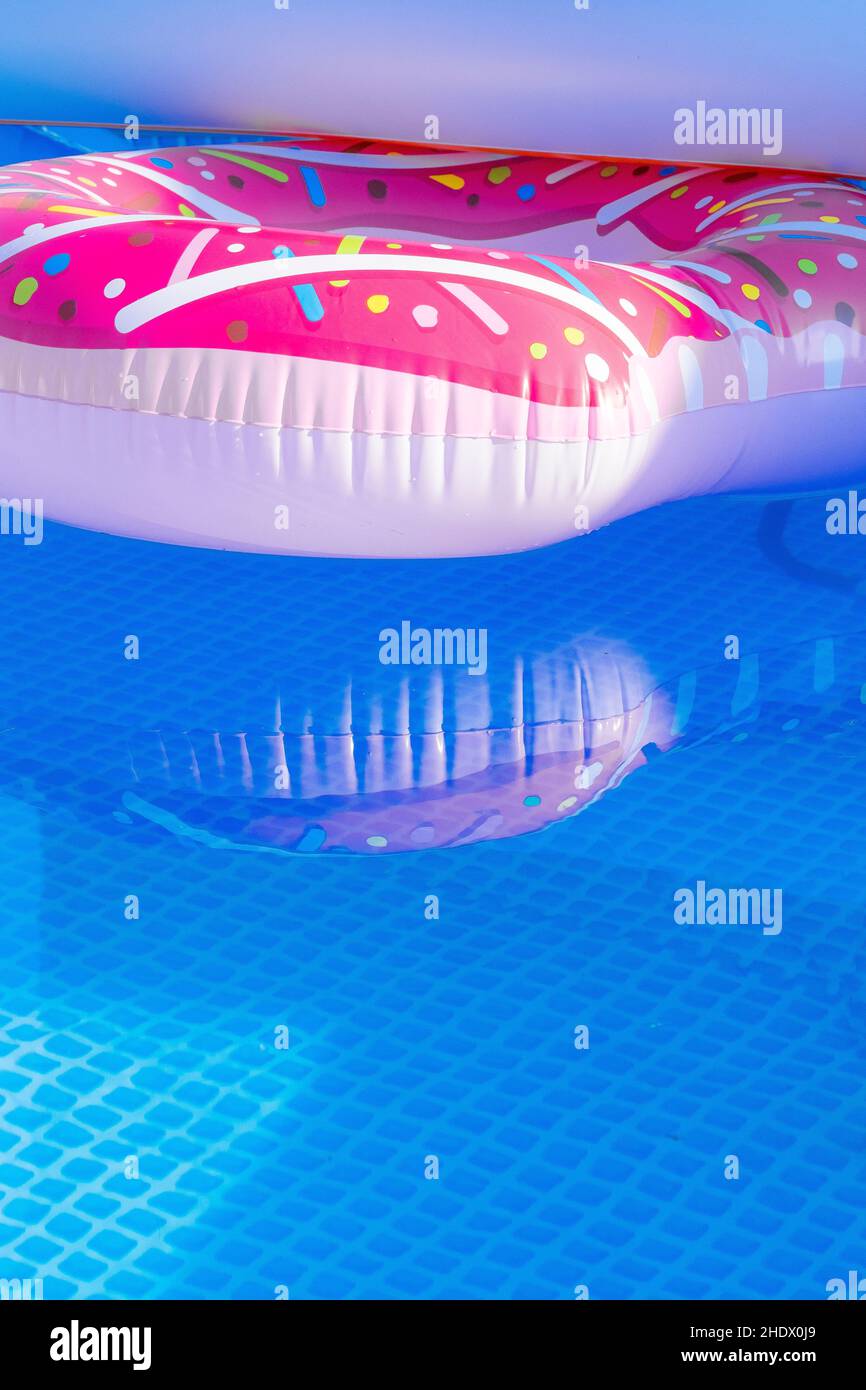 A colourful inflatable plastic ring floating in an outdoor pool. Stock Photo