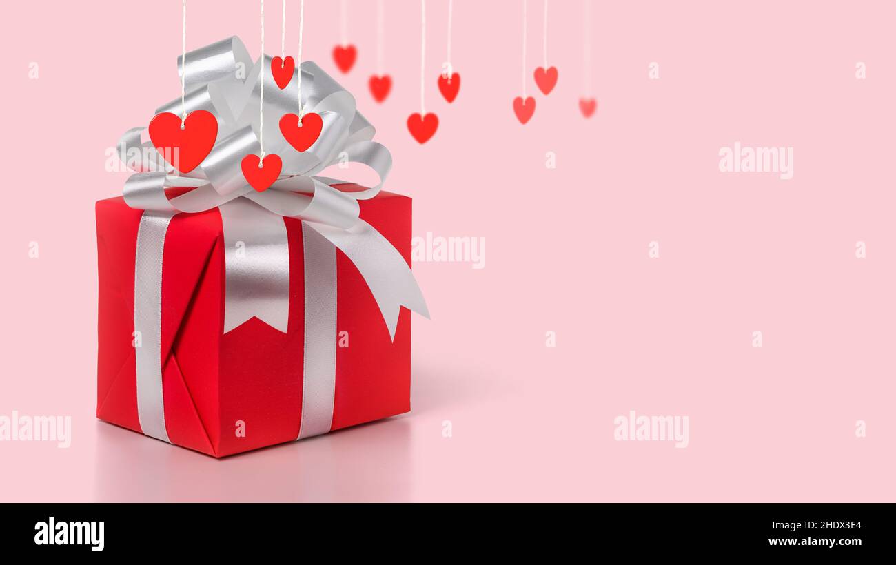 Gift Red Rope Red Gift box with silver bow and red hearts on a ropes on a pink ...