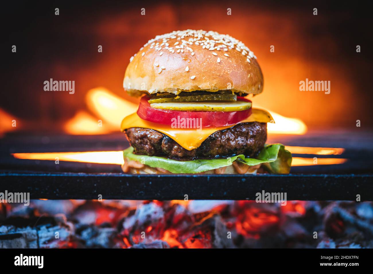 Juicy classic burger on a charcoal barbecue grill with natural fire in ...