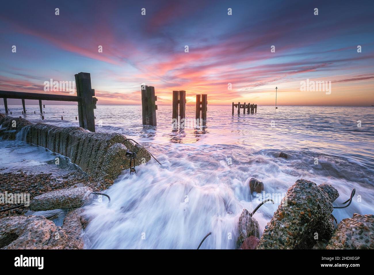 Bawdsey at Sunrise with waves crashing through old sea defences, Suffolk UK Stock Photo