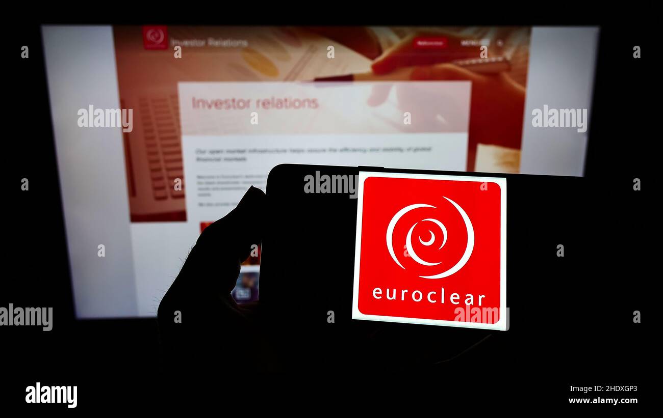 Person holding smartphone with logo of Belgian financial company Euroclear Group on screen in front of website. Focus on phone display. Stock Photo