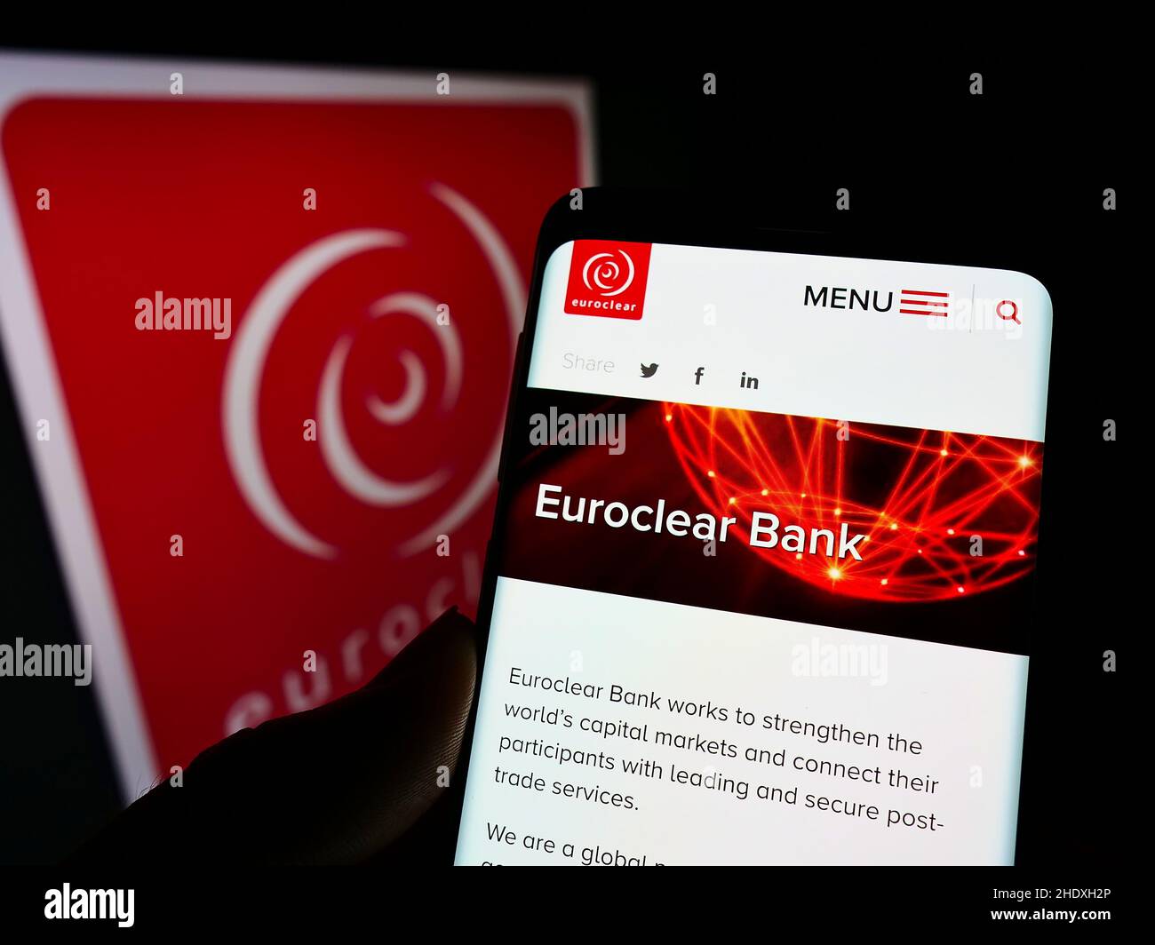 Person holding smartphone with webpage of Belgian financial company Euroclear Group on screen in front of logo. Focus on center of phone display. Stock Photo
