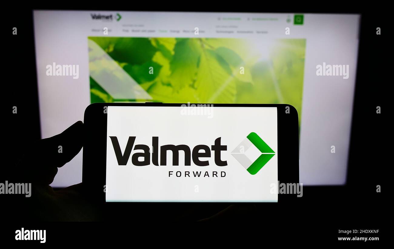 Person holding smartphone with logo of Finnish engineering company Valmet Oyj on screen in front of website. Focus on phone display. Stock Photo