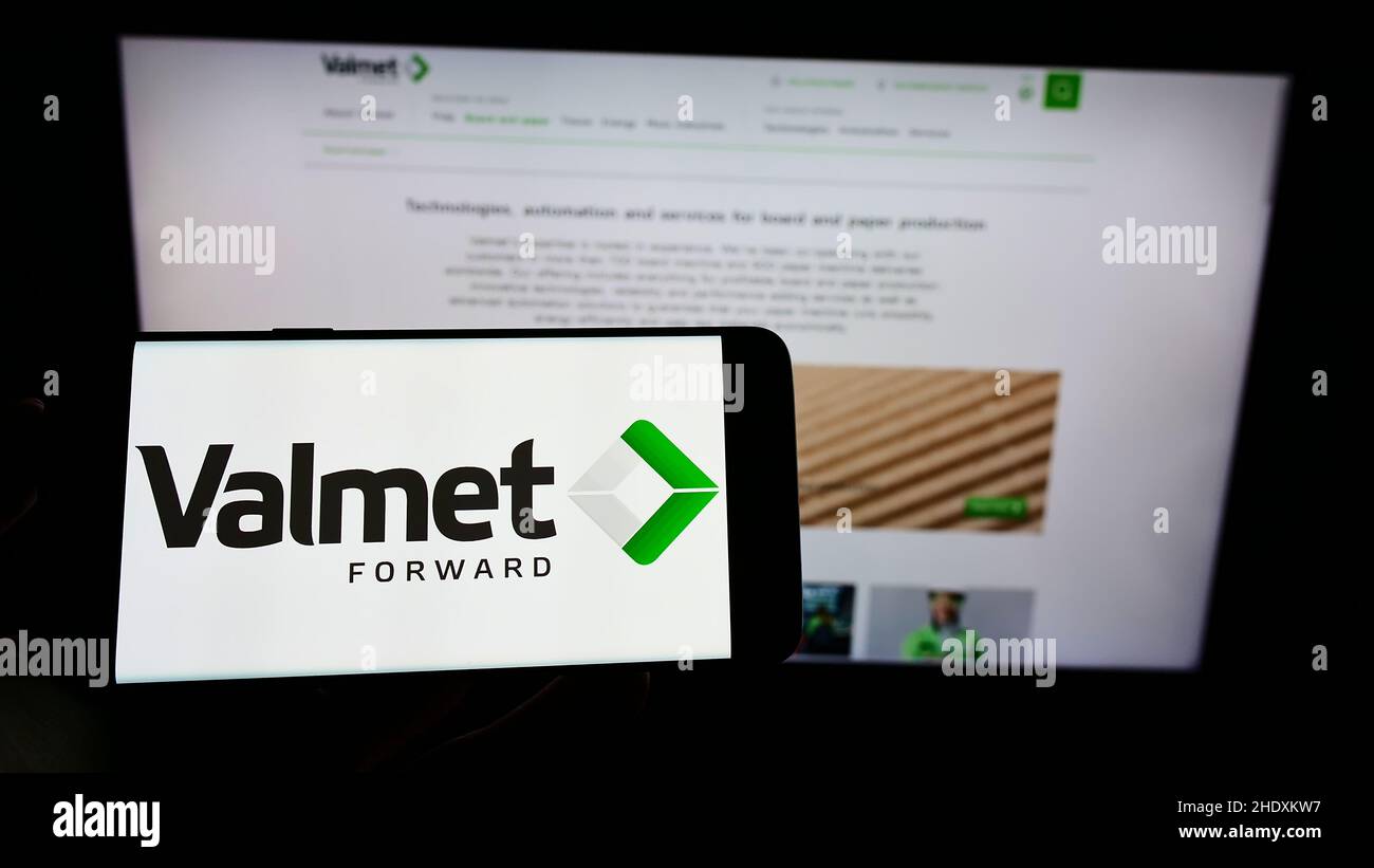 Person holding cellphone with logo of Finnish engineering company Valmet Oyj on screen in front of business webpage. Focus on phone display. Stock Photo