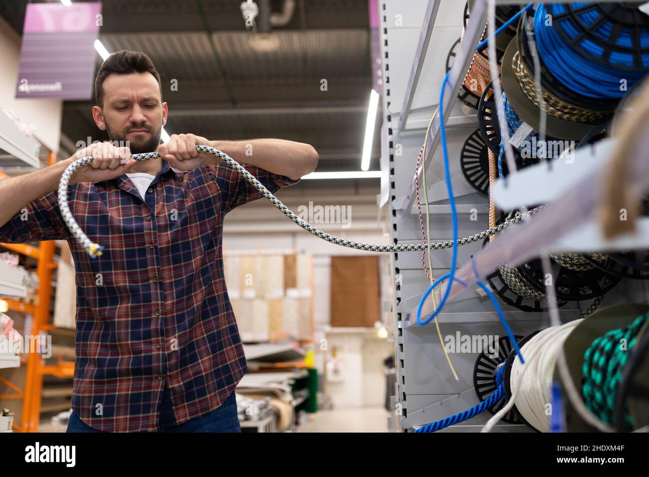 Testing Rope In Hardware Store a man in a hardware store checks the strength of the safety ropes and ...