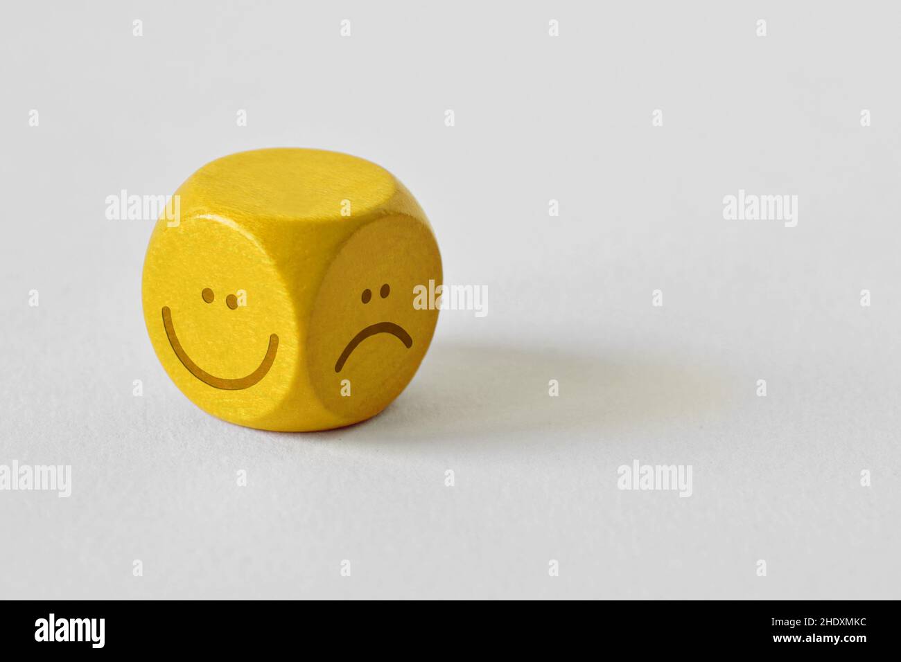 Yellow dice with positive and negative expression on white background Stock Photo