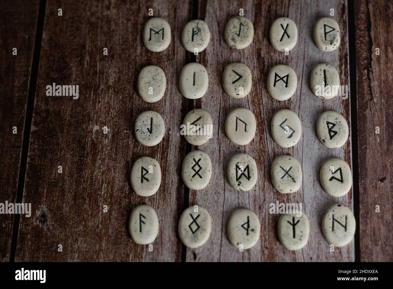 rune stones with black symbols for fortune telling on a wooden table Stock Photo
