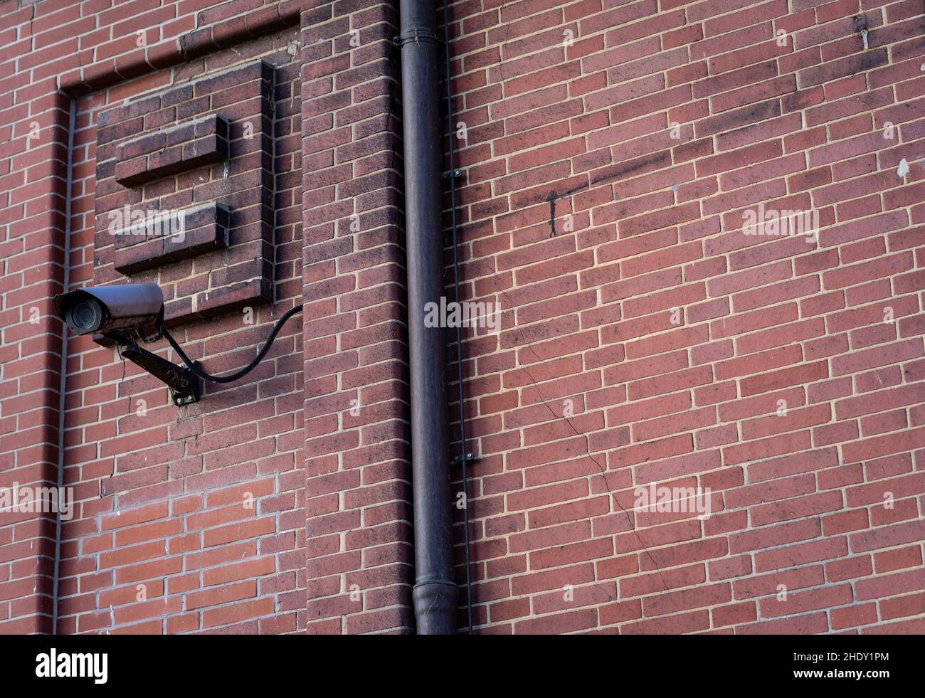 Monitoring Camera mounted on an outer wall made of red bricks. Stock Photo