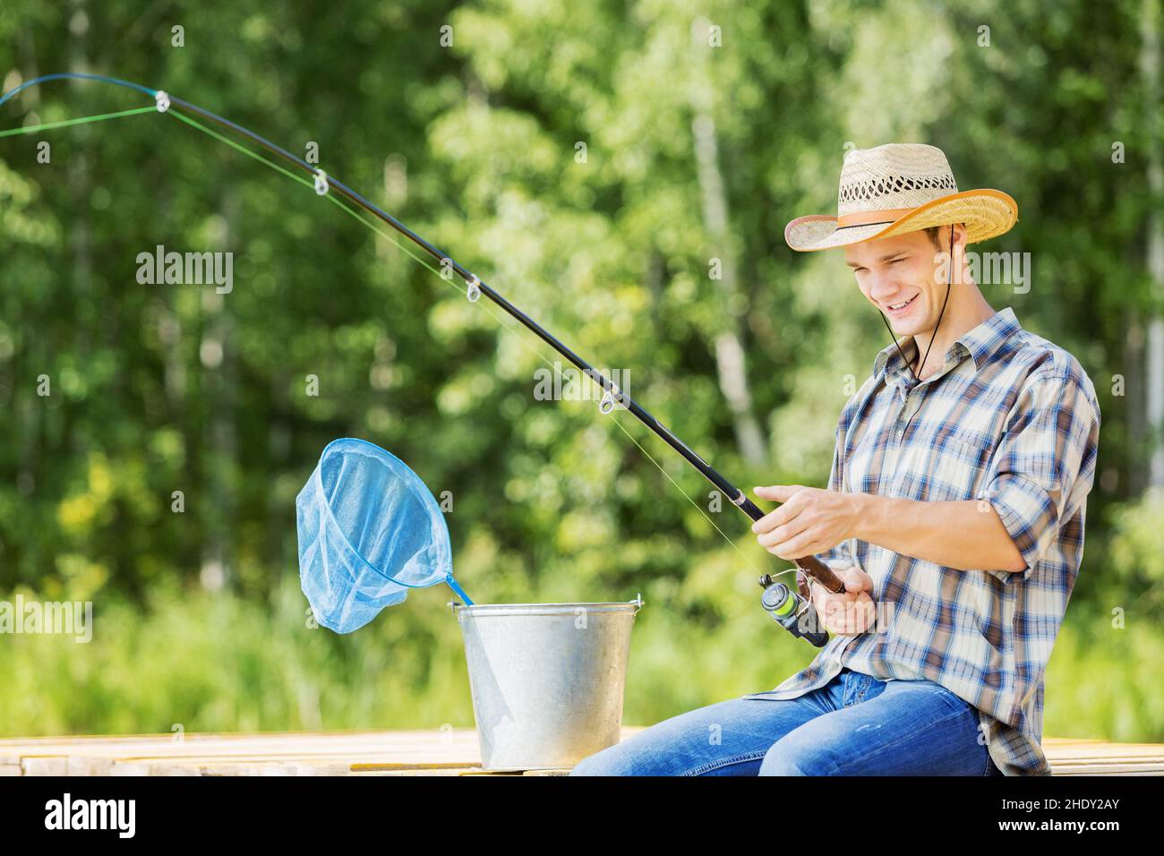 Men holding fishing rods and bucket with fresh caught fish outdoors. Close-up  view with no face Stock Photo - Alamy