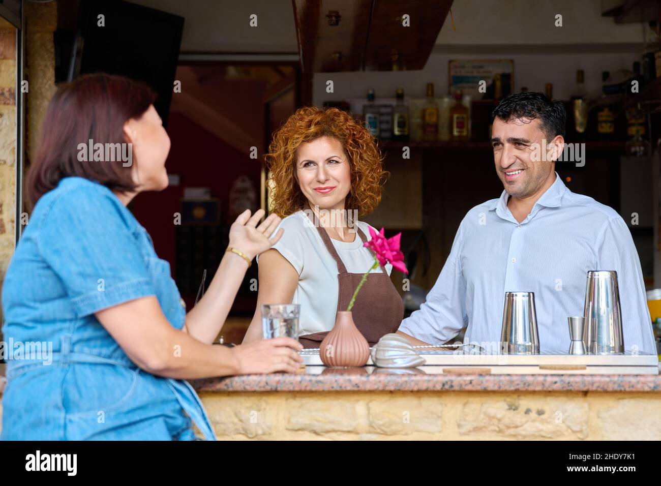 Couple working at the bar in an outdoor cafe talking to a female client Stock Photo