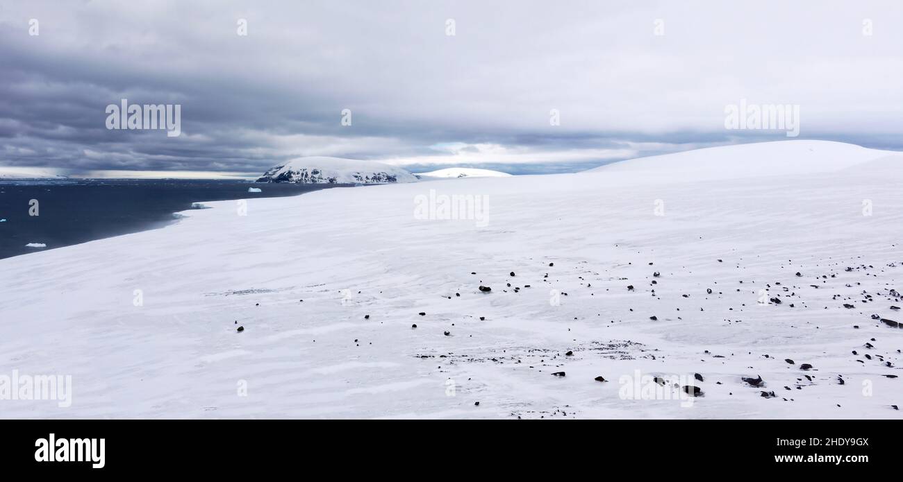 Panoramic view of the snowy lower slopes  of Brown Bluff on the northern Antarctic peninsula. The landscape is strewn with basalt rock. Stock Photo