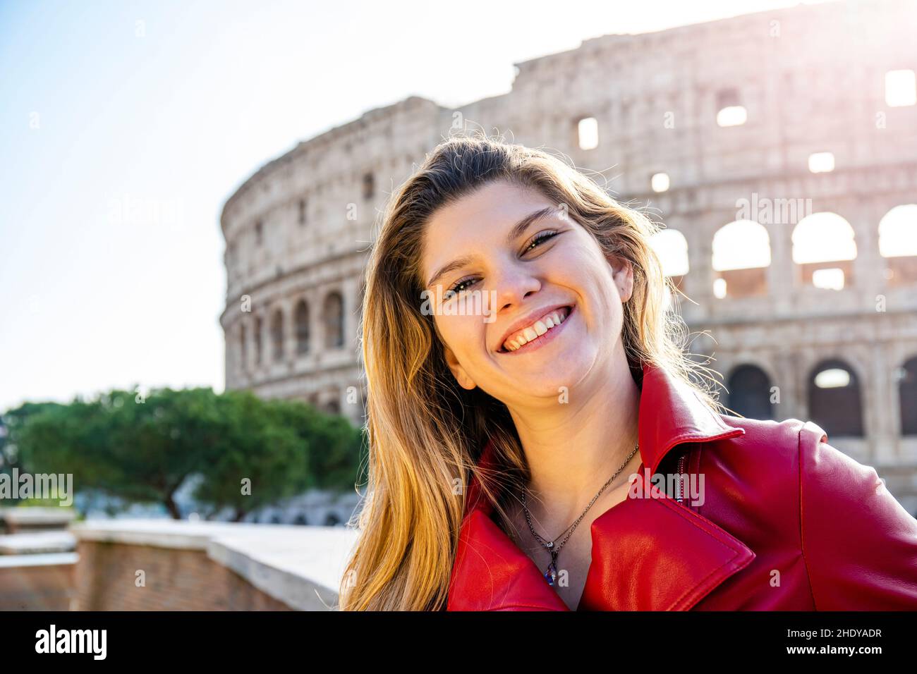 Young woman traveling to Rome. Backlight portrait of a young blonde woman smiling. On the background the Colosseum and on the right the Copy space for Stock Photo