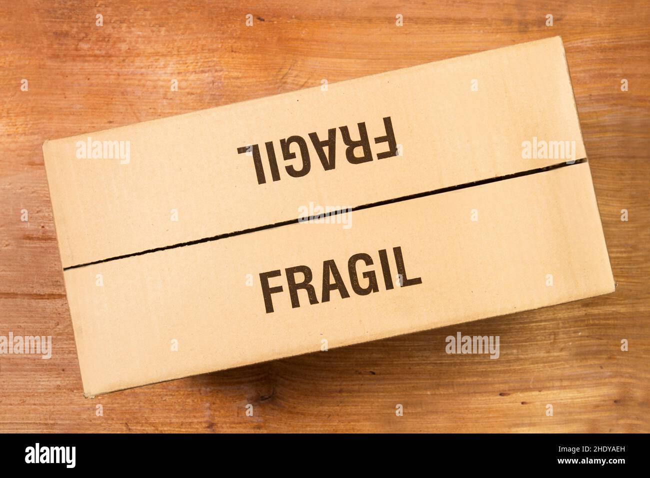 A cardboard box on a wooden background in a top view (fragile) Stock Photo