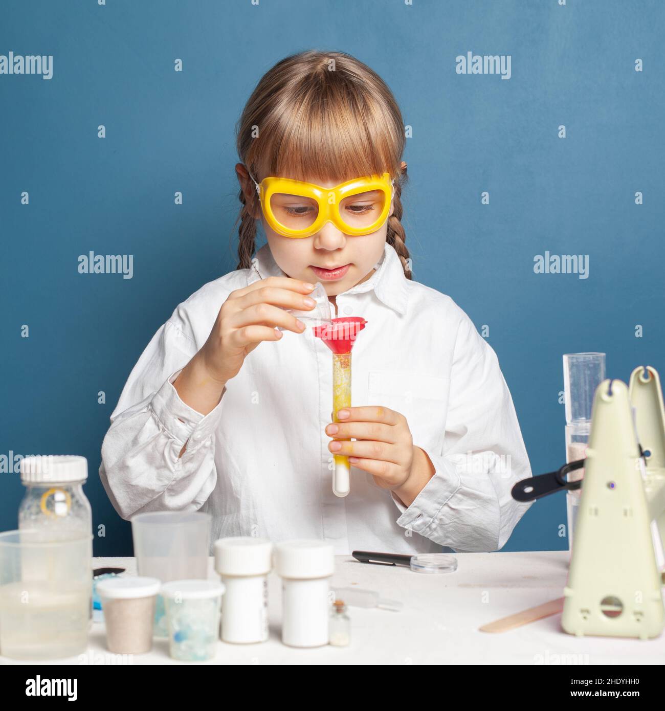 Curious schoolgirl pouring reagent into flask Stock Photo
