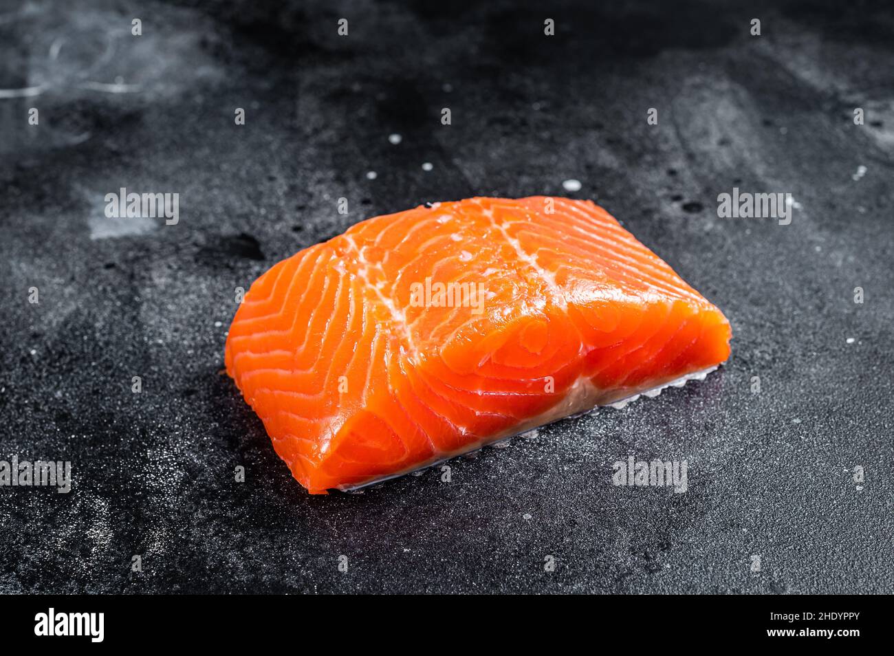 Raw salmon fillet steaks on kitchen table. Black background. Top view ...