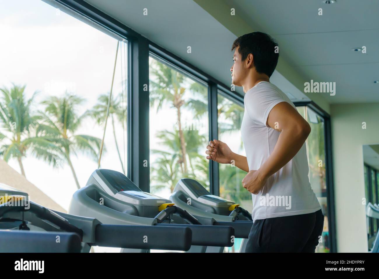Asian man working out on a treadmill at a resort fitness center in the morning. Stock Photo