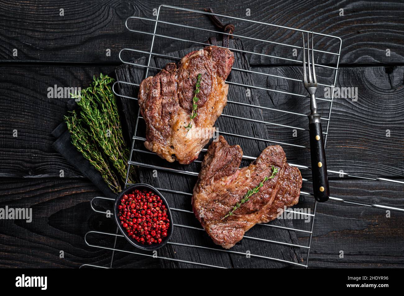 BBQ Grilled Chuck eye Roll beef steaks on grill. Black Wooden