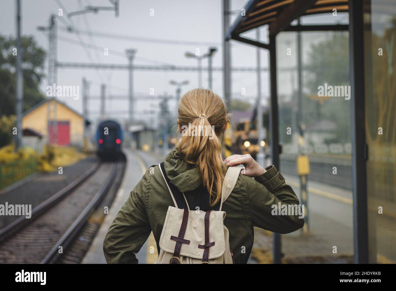 Woman with backpack is looking at the departing train. Travelling during autumn season. Travel concept Stock Photo