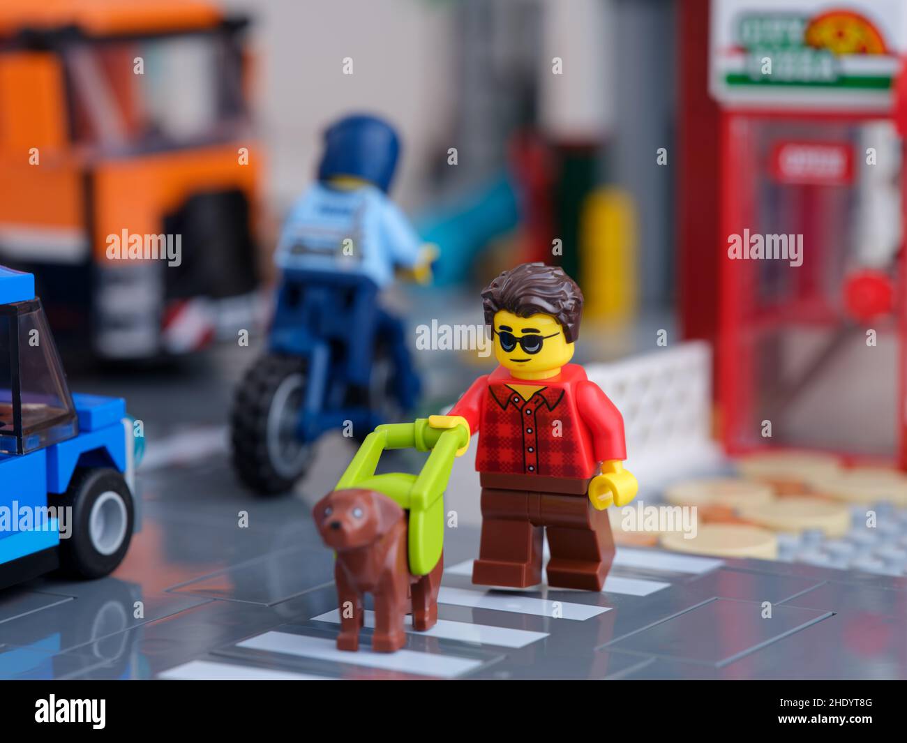 Tambov, Russian Federation - January 07, 2022 A Lego blind or partially-sighted person minifigure with a guide dog crossing the road using a pedestria Stock Photo