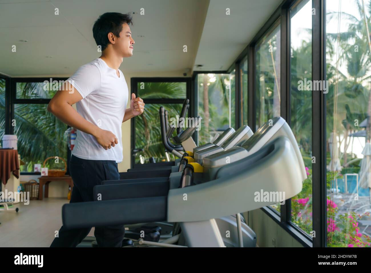 Asian man working out on a treadmill at a resort fitness center in the morning. Stock Photo