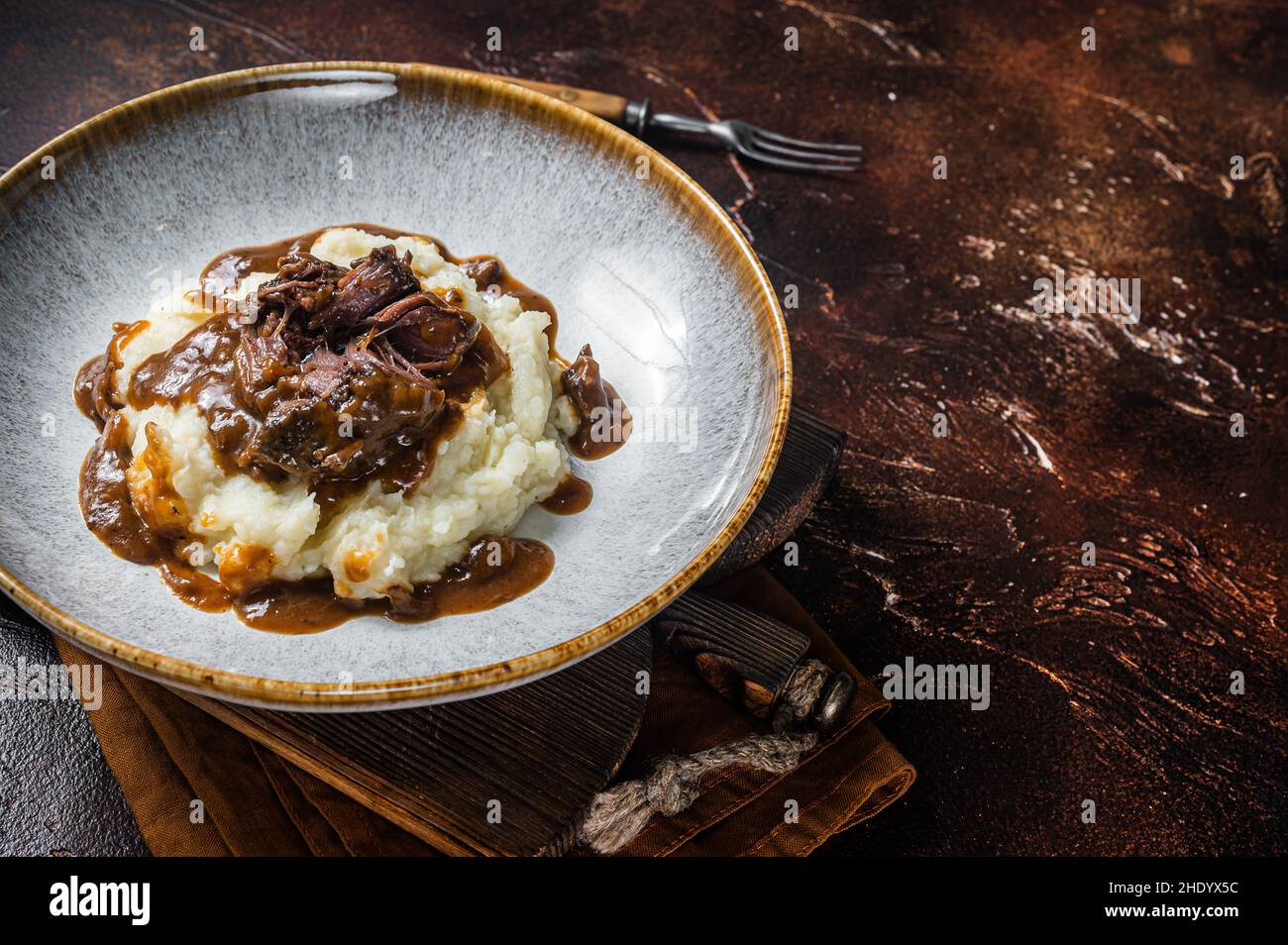 Slow cooked beef cheeks in red wine sauce with mashed potato. Dark