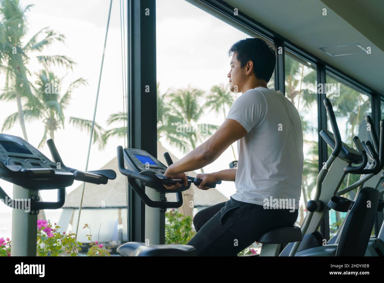 Asian man working out on indoor cycling at a resort fitness center in the morning. Stock Photo