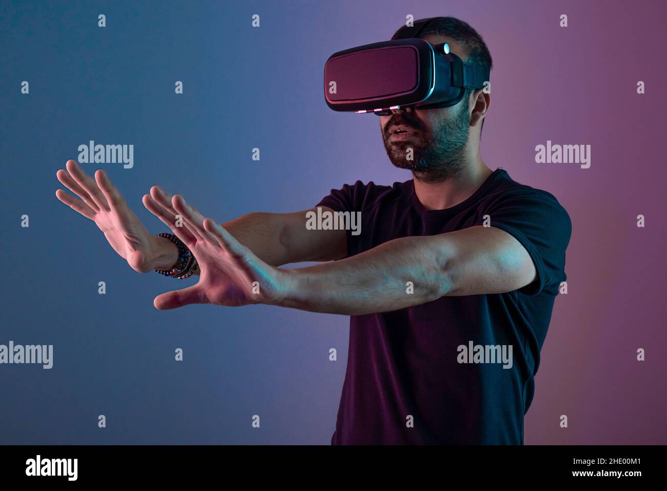 Young man in VR glasses headset interact with virtual reality in color ...