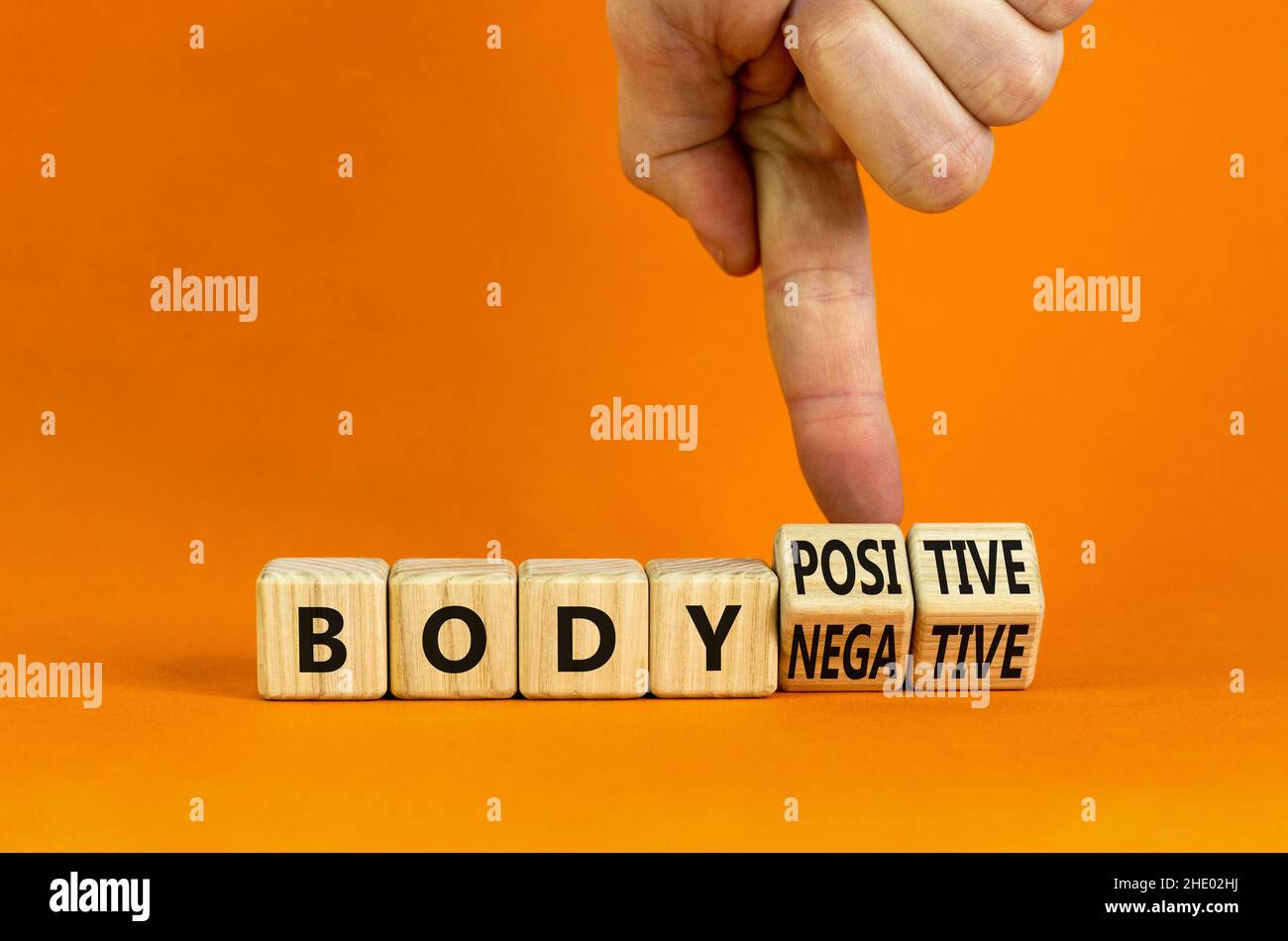 Body positive or negative symbol. Psychologist turns cubes, changes words body negative to body positive. Beautiful orange background, copy space. Psy Stock Photo