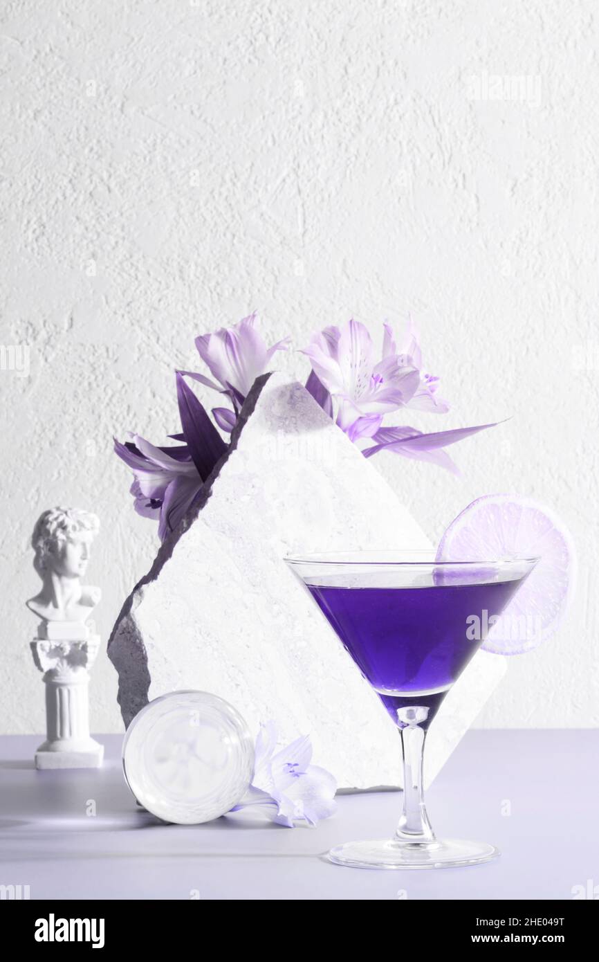 cocktail drink near the stone and flowers toned in trendy Very Peri. color of the year. Creative party concept. beautiful photo for flyer. Stock Photo