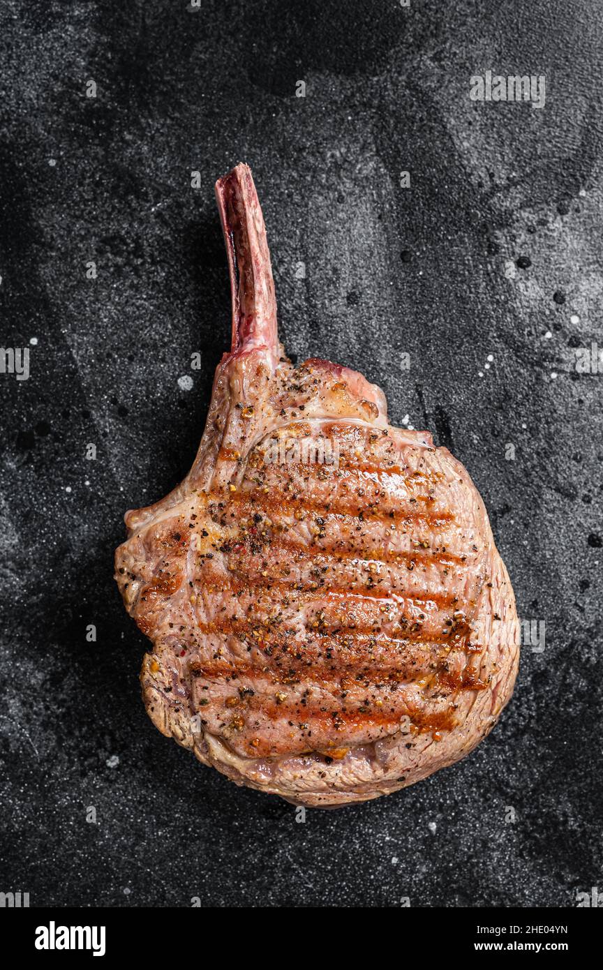 BBQ Grilled Tomahawk beef veal steak on butcher table. Black background